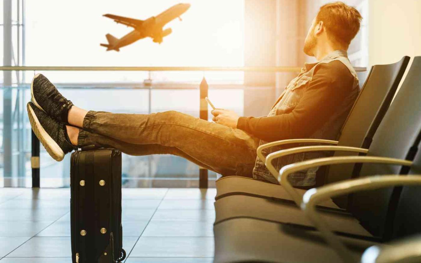 A man sitting on a bench watching a plane take off